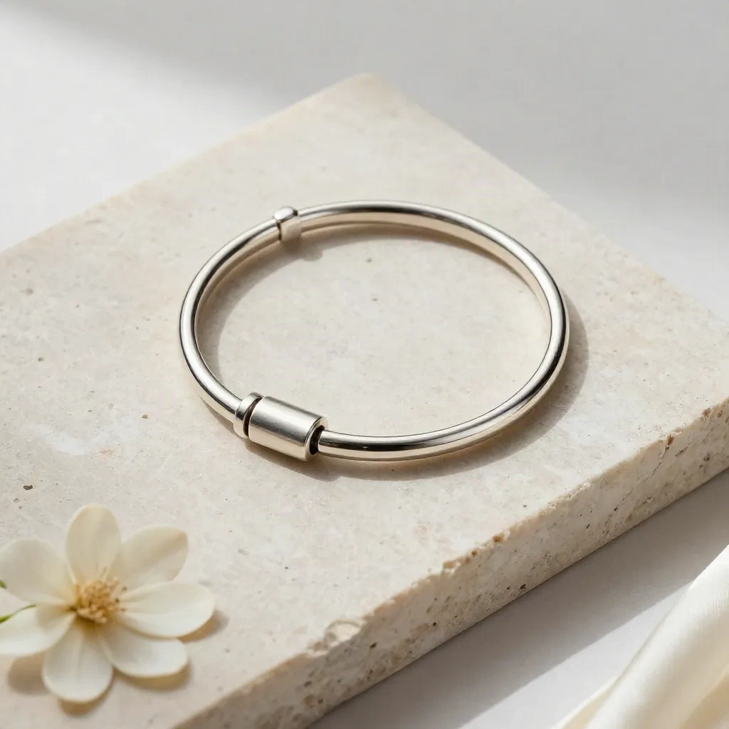 Bracelet argent poli sur pierre claire avec petite fleur fanée, vue de dessus élégante.